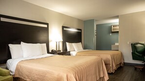 Een hotelkamer met twee bedden, een bureau, een stoel en een lamp.