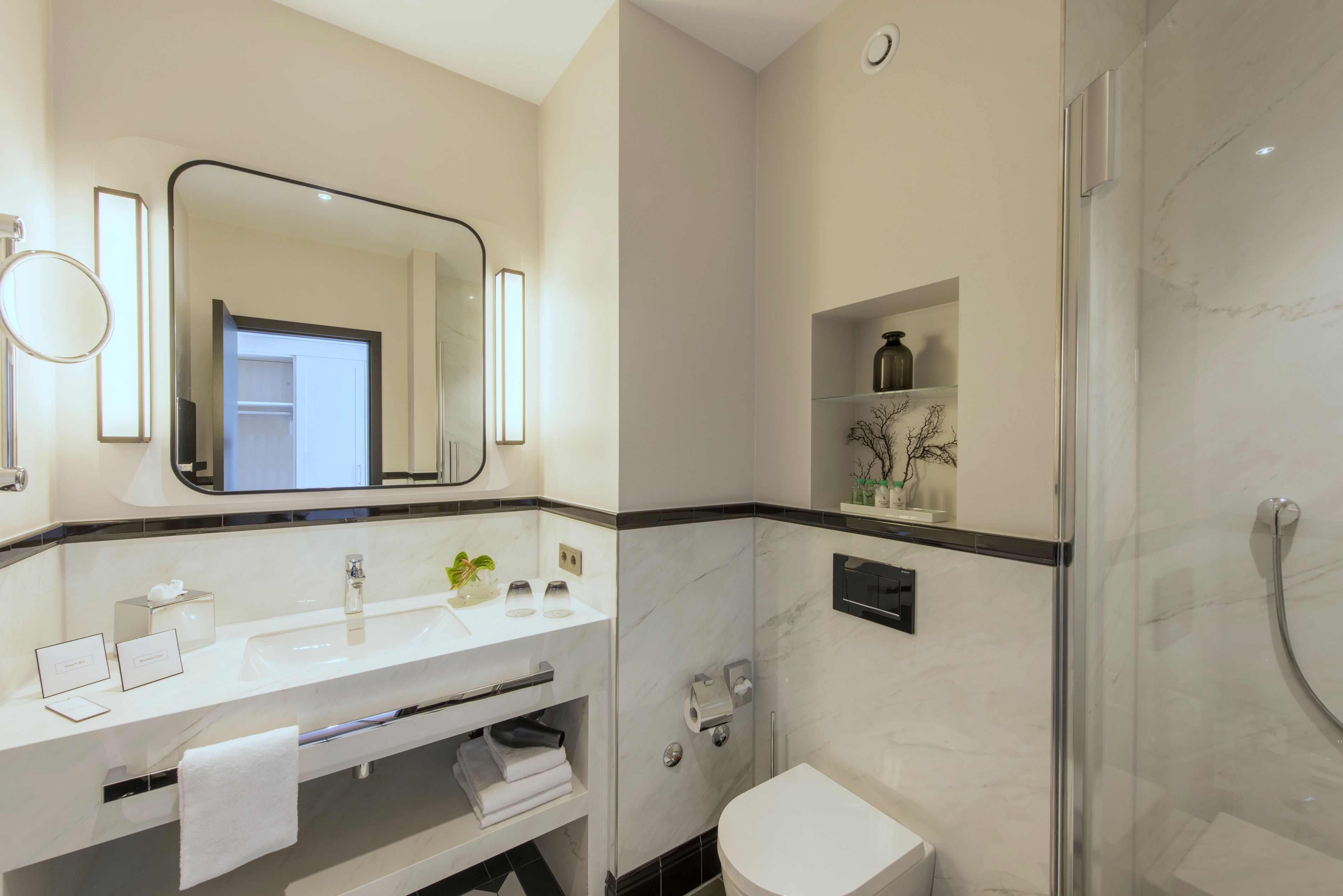 Un baño moderno con un espejo grande, un lavabo, un inodoro y una ducha.