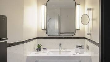 Une salle de bain moderne avec un grand miroir, un lavabo et une douche.