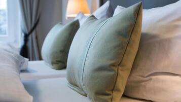 Ein Bett mit Kissen und einer Lampe im Hintergrund.