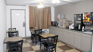 A kitchen with a refrigerator, coffee maker, and a microwave. There are four chairs and a table. - Econo Lodge Franklin South (Franklin)