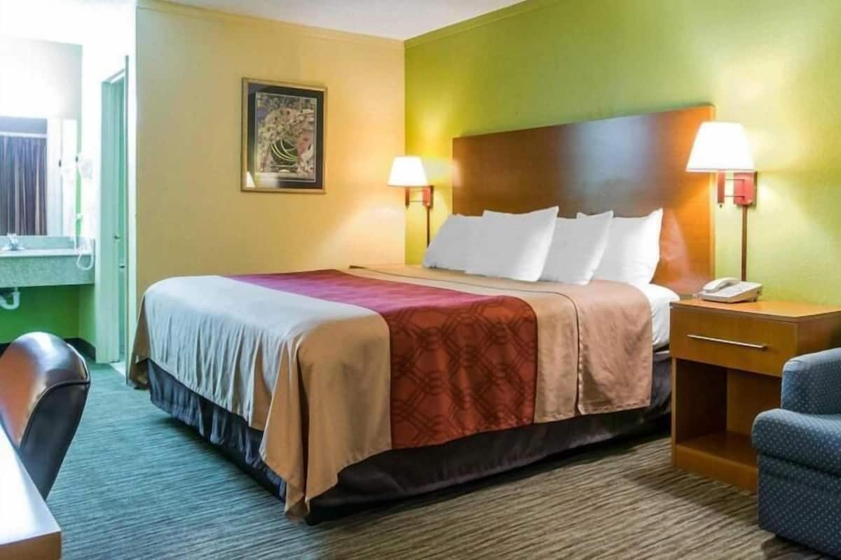 A hotel room with a bed, bedside lamps, a desk, and a chair.
