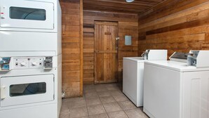 Un cuarto de lavandería con lavadoras y secadoras apiladas, paredes de madera y suelo de baldosas.