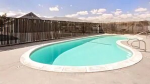 Una piscina con valla y cielo despejado.