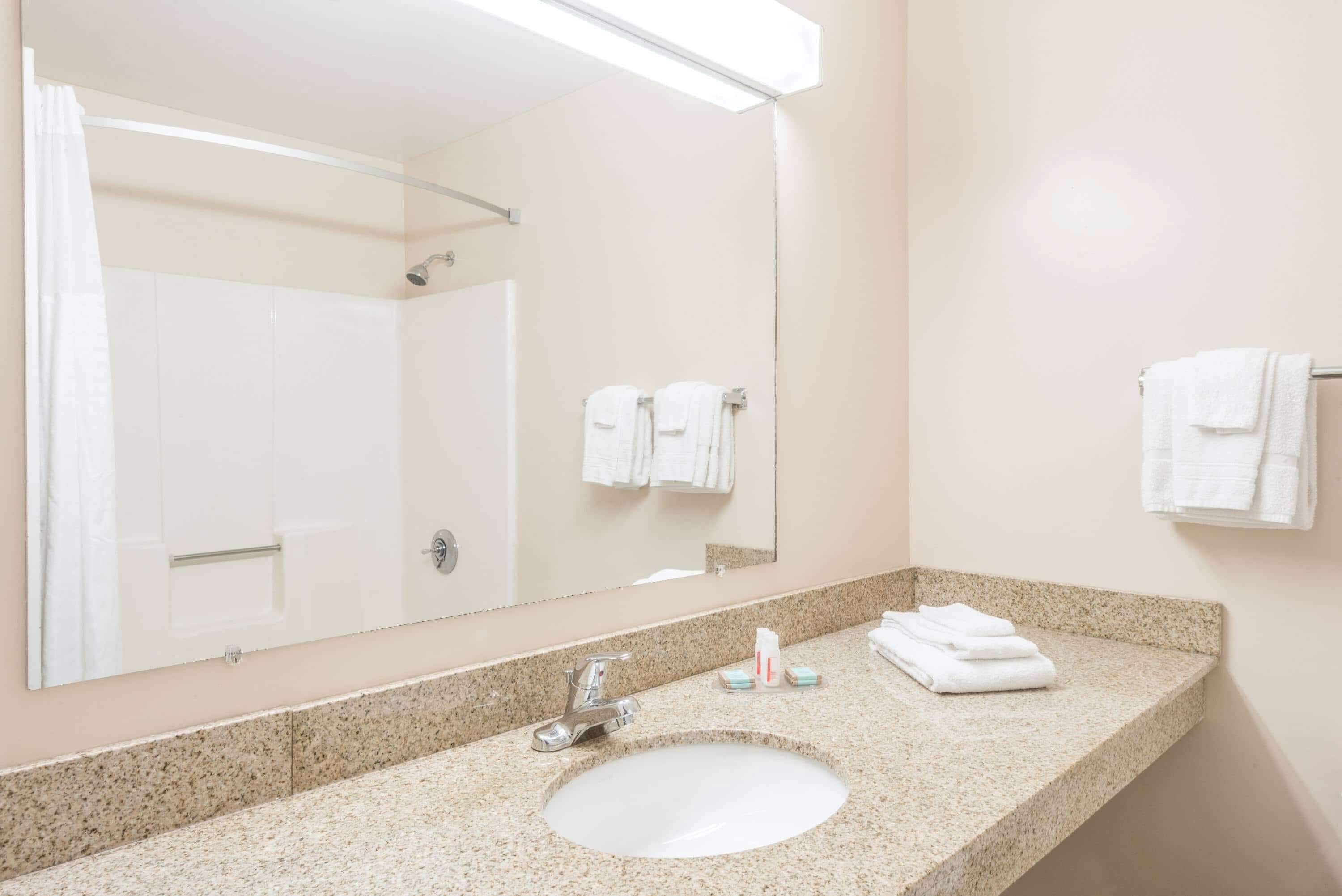 A bathroom with a sink, mirror, and towel rack.