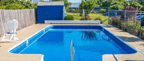 Una piscina rectangular con una escalera metálica en el centro, rodeada por una solana de concreto.