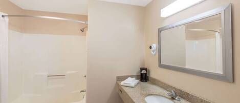 Un baño moderno con bañera, lavamanos y un espejo grande.