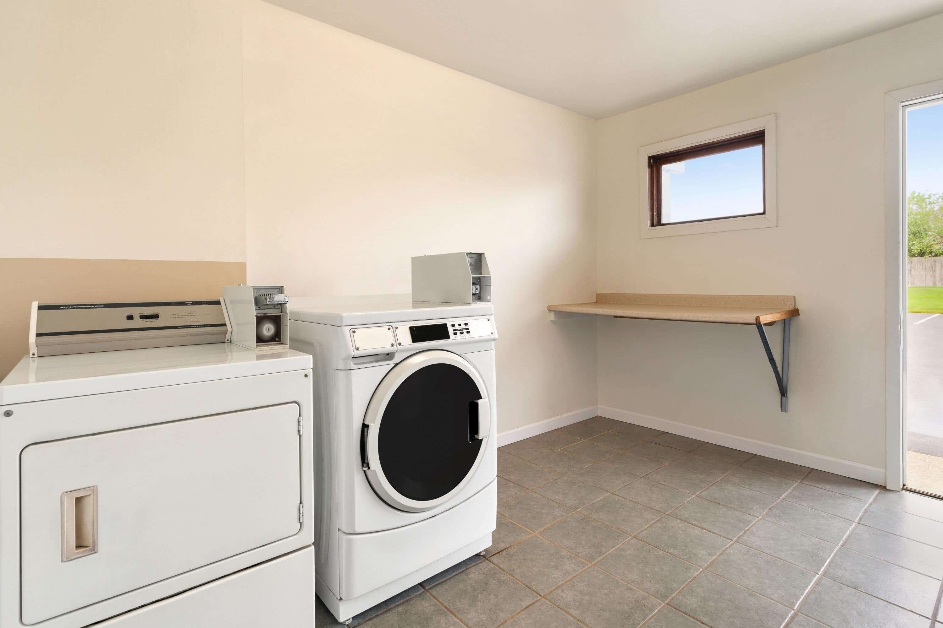 A laundry room with a washing machine, dryer, and a small shelf.