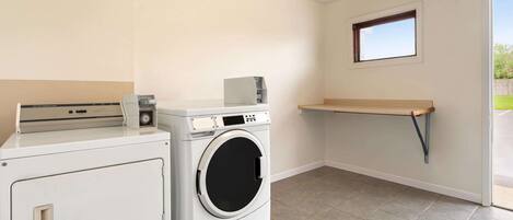 A laundry room with a washing machine, dryer, and a small shelf.