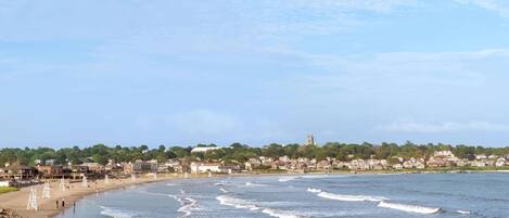 A coastal town with a beach, houses, and a church on a hill.
