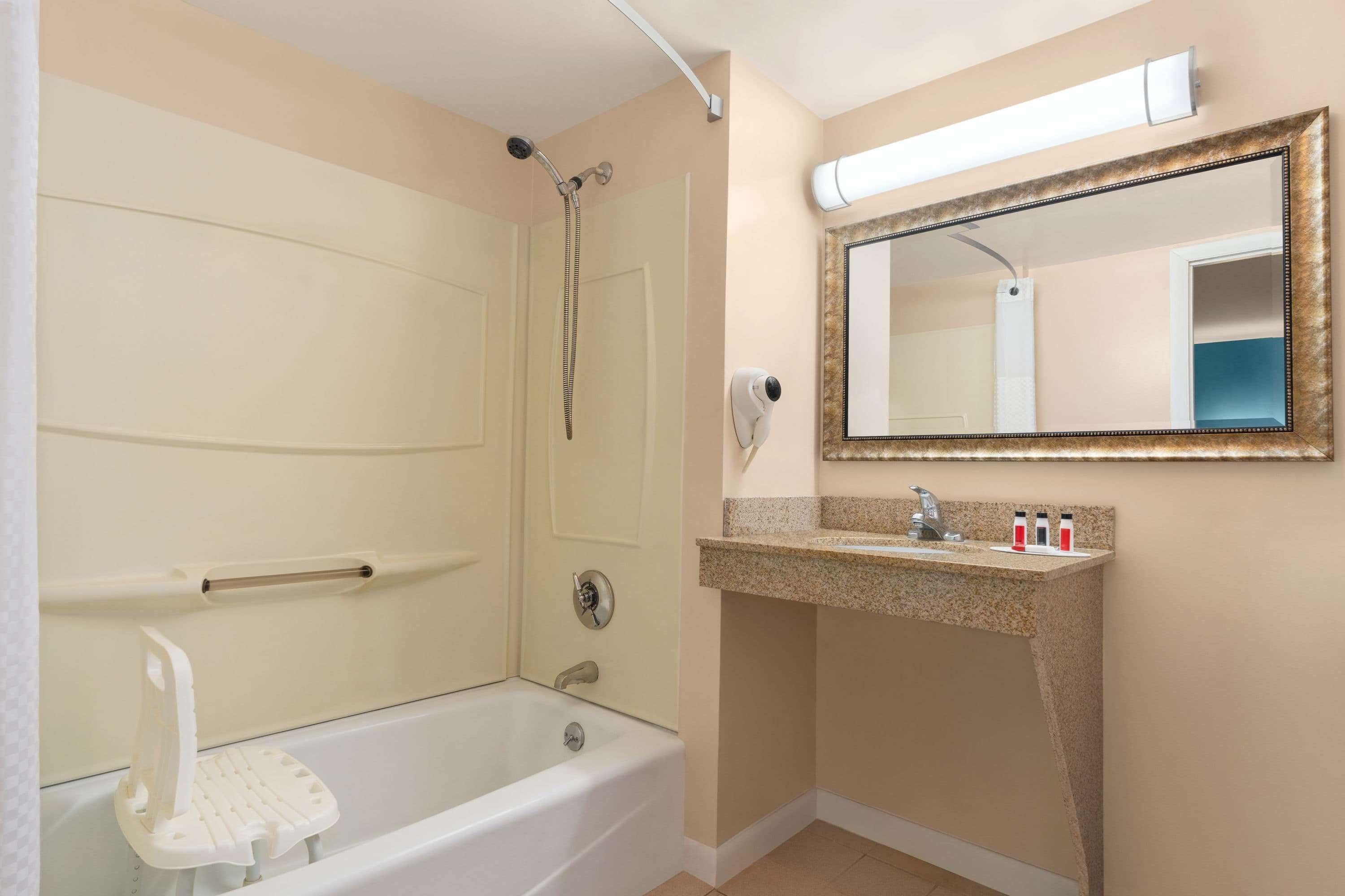 A bathroom with a bathtub, a shower, a vanity with a mirror, and a towel rack.