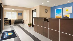 A hotel reception area with a reception desk, a clock, and a window with curtains. - Days Inn by Wyndham Middletown/Newport Area (Middletown)