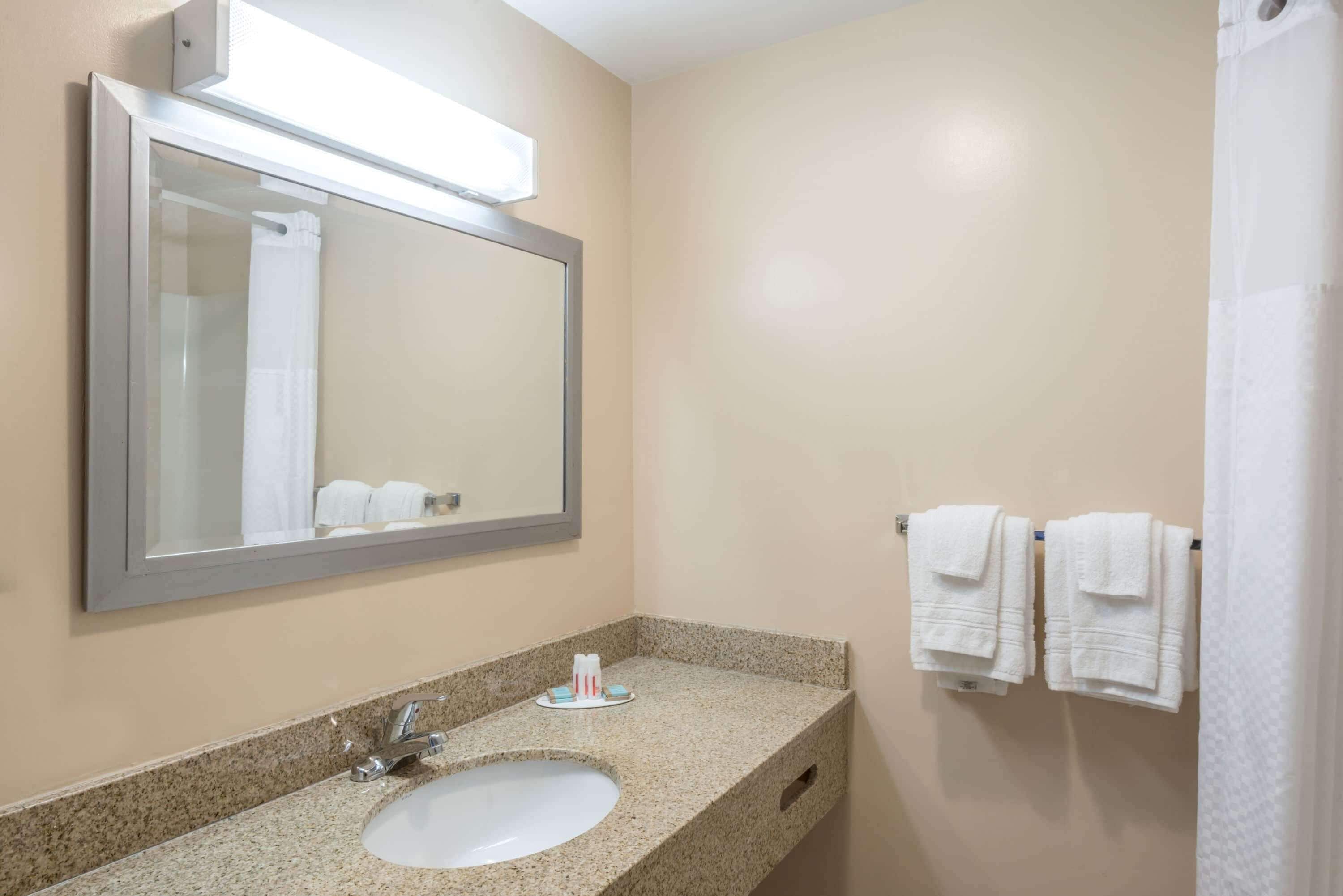 A bathroom with a sink, mirror, and towel rack.