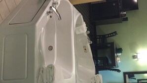 A bathroom with a large bathtub, a mirror, and a sink. - University Manor Inn (Buffalo)