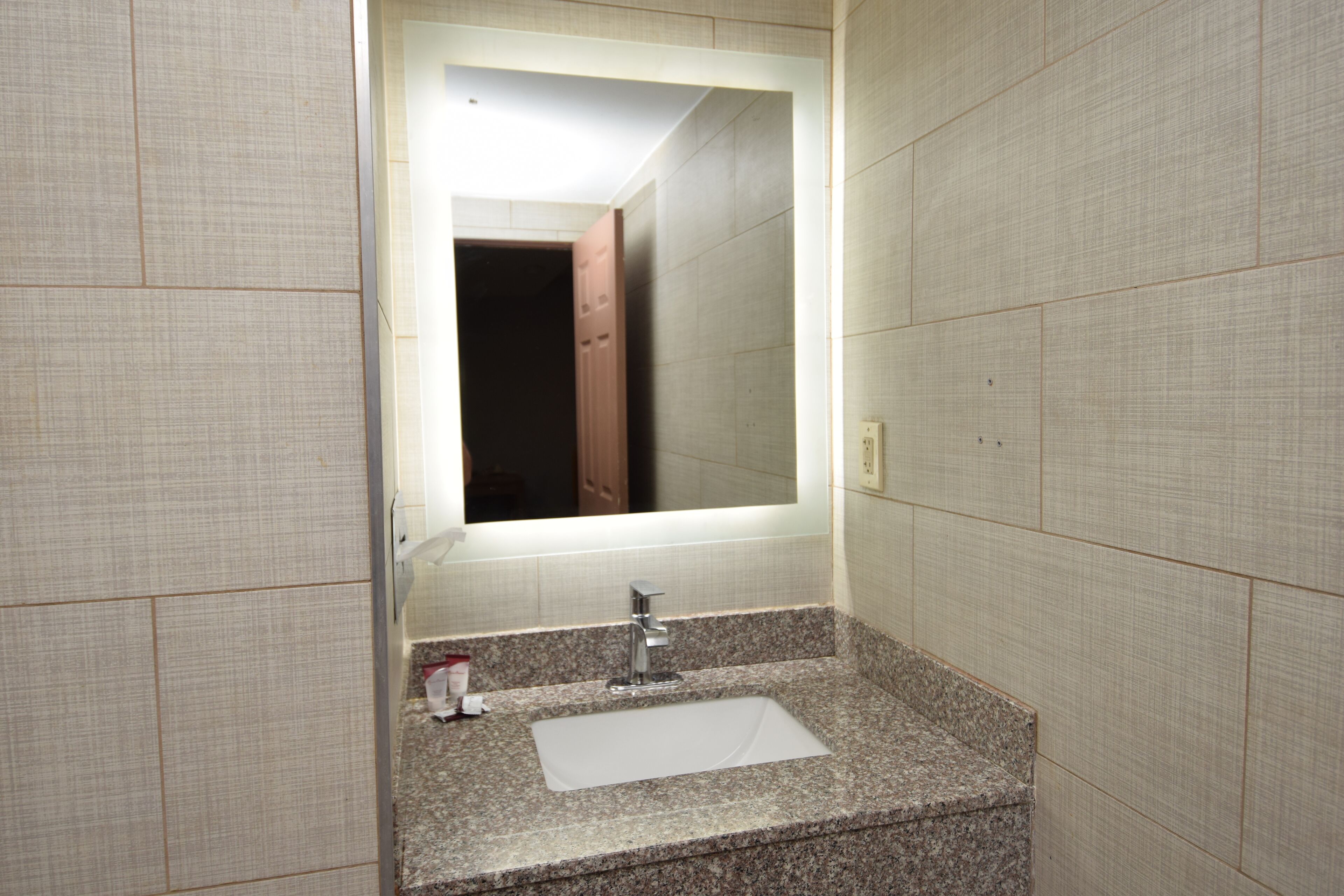 A bathroom with a sink, mirror, and tiled walls.