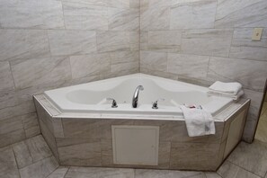 Une salle de bain d’angle avec une baignoire sur pieds, un porte-serviettes et une bouche d’aération.