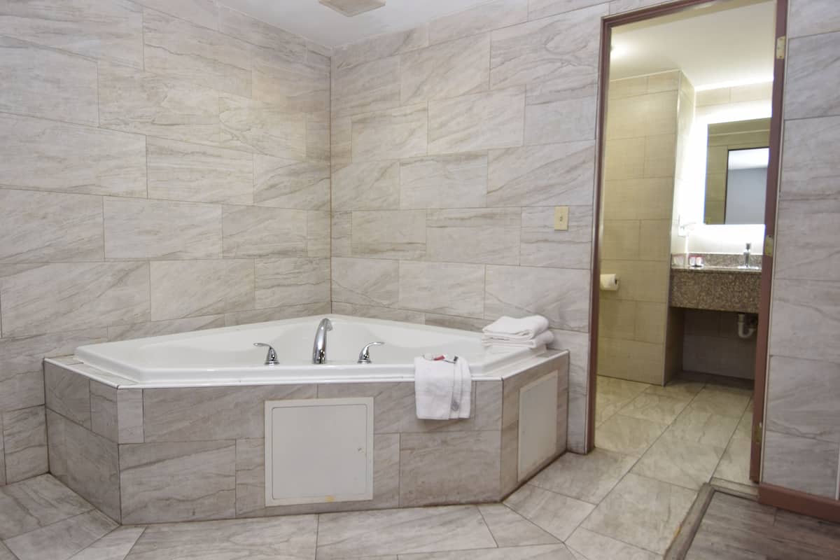 Un baño moderno con una bañera grande, paredes de mármol y una zona de ducha a la vista.