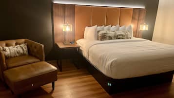 Une chambre d’hôtel avec un grand lit, un fauteuil en cuir et deux lampes de chevet.
