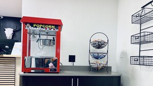 Popcorn-kone ja välipalojen esillepanoteline huoneessa, jossa on myös tiski ja kaappeja.