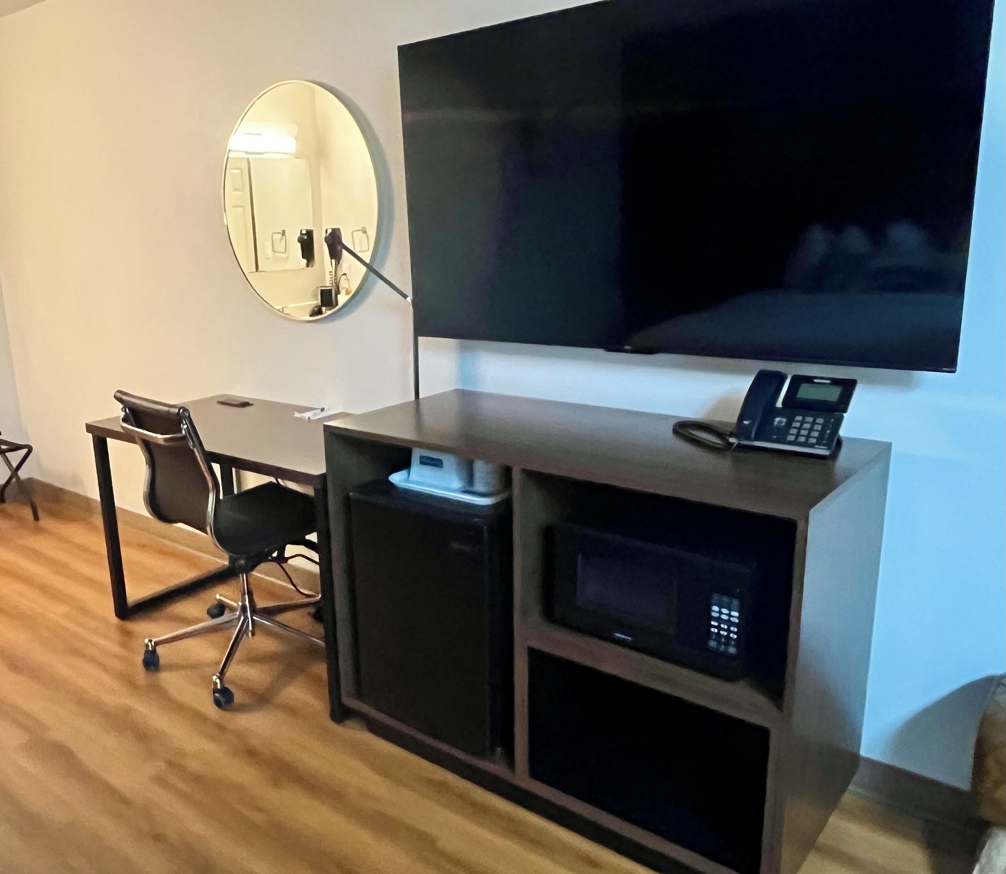 A modern office space with a desk, chair, and a large flat-screen TV mounted on the wall.