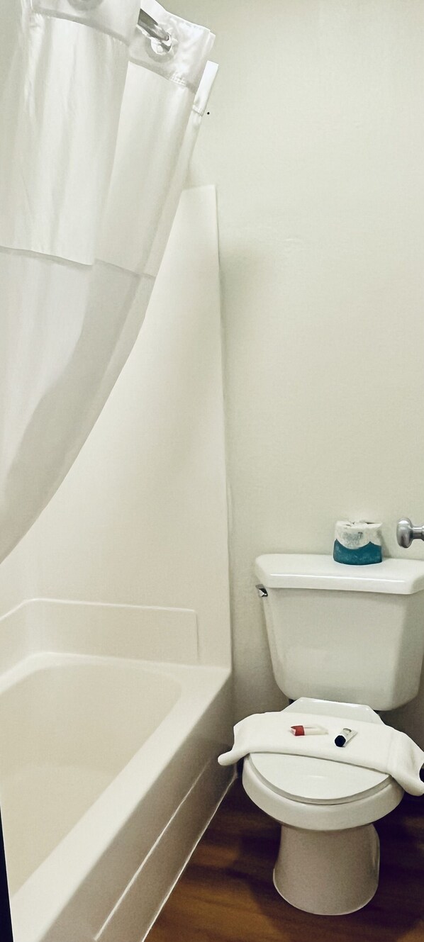 Un baño con bañera, inodoro y cortina de ducha.