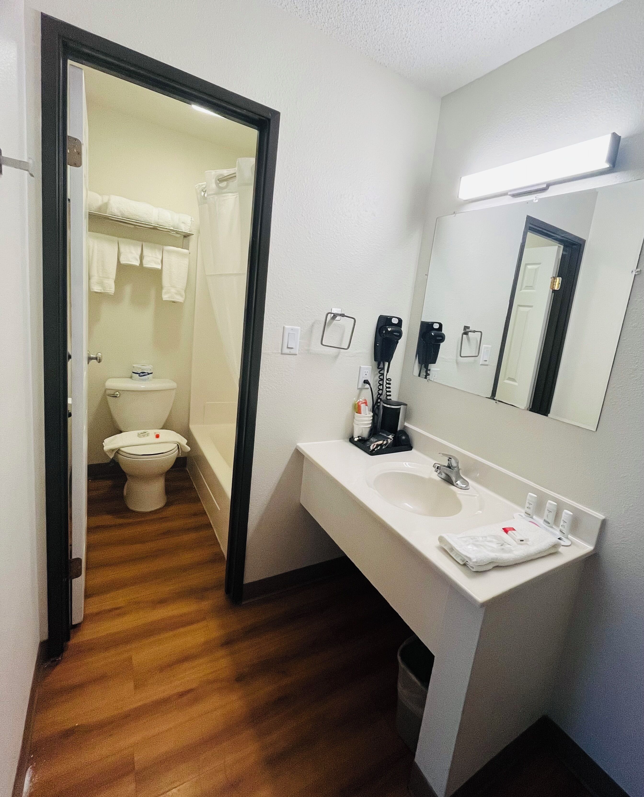 Een badkamer met toilet, wastafel en spiegel.