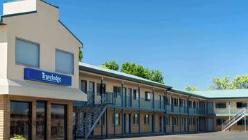 Um motel Travelodge com estrutura em dois andares, vários quartos e uma escadaria central.