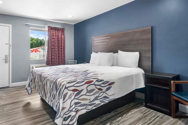 Una habitación de hotel moderna con una cama grande, una mesita de noche y vistas al exterior.