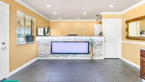 A living room with a fireplace, a flat-screen TV, and a stone accent wall. - Americas Best Value Inn & Suites Siloam Springs (Siloam Springs)