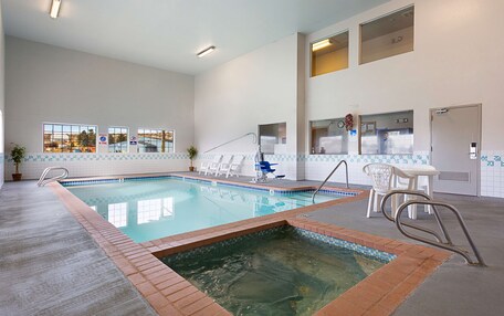 An indoor swimming pool with a tiled edge, a diving board, and a lifeguard stand.