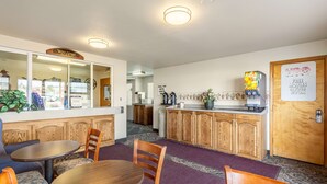 A hotel lobby with a reception desk, a 'Welcome' sign, a kitchen area, and a 'Free Movies in Your Room' sign. - Americas Best Value Inn Burns (Burns)