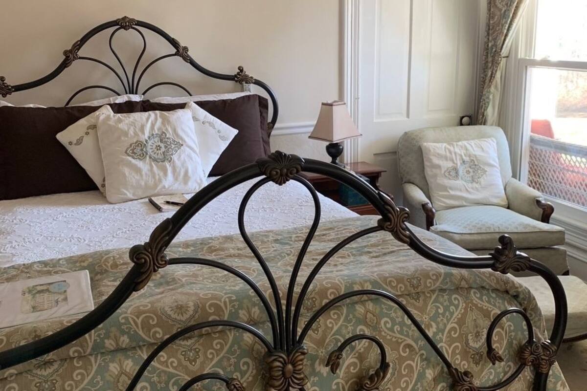 Une chambre à coucher avec un lit, une chaise, une fenêtre avec des rideaux et une porte.