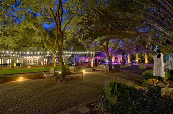 An outdoor area with a paved walkway, benches, and string lights.
