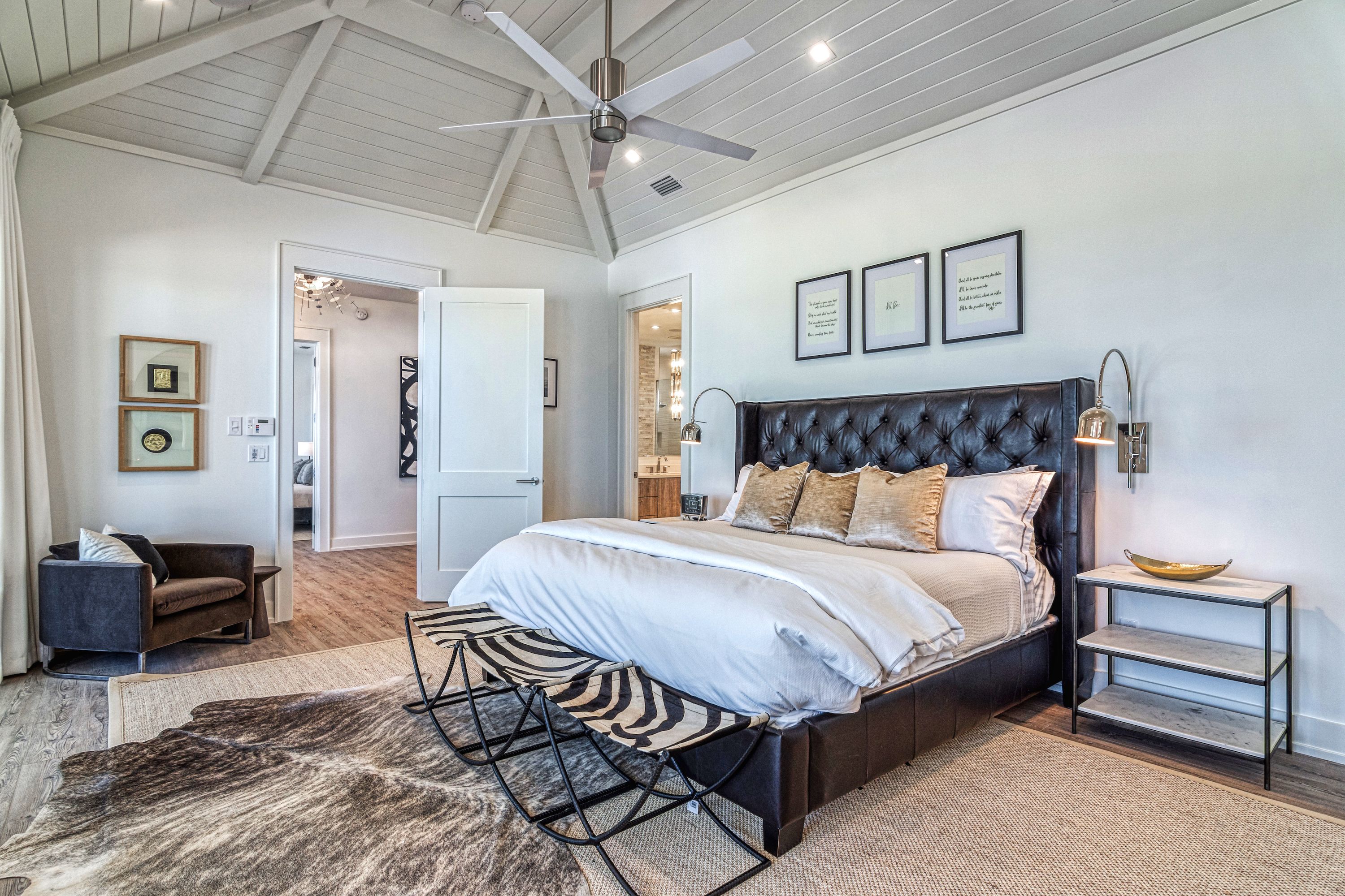 A bedroom with a large bed, a ceiling fan, and a nightstand.