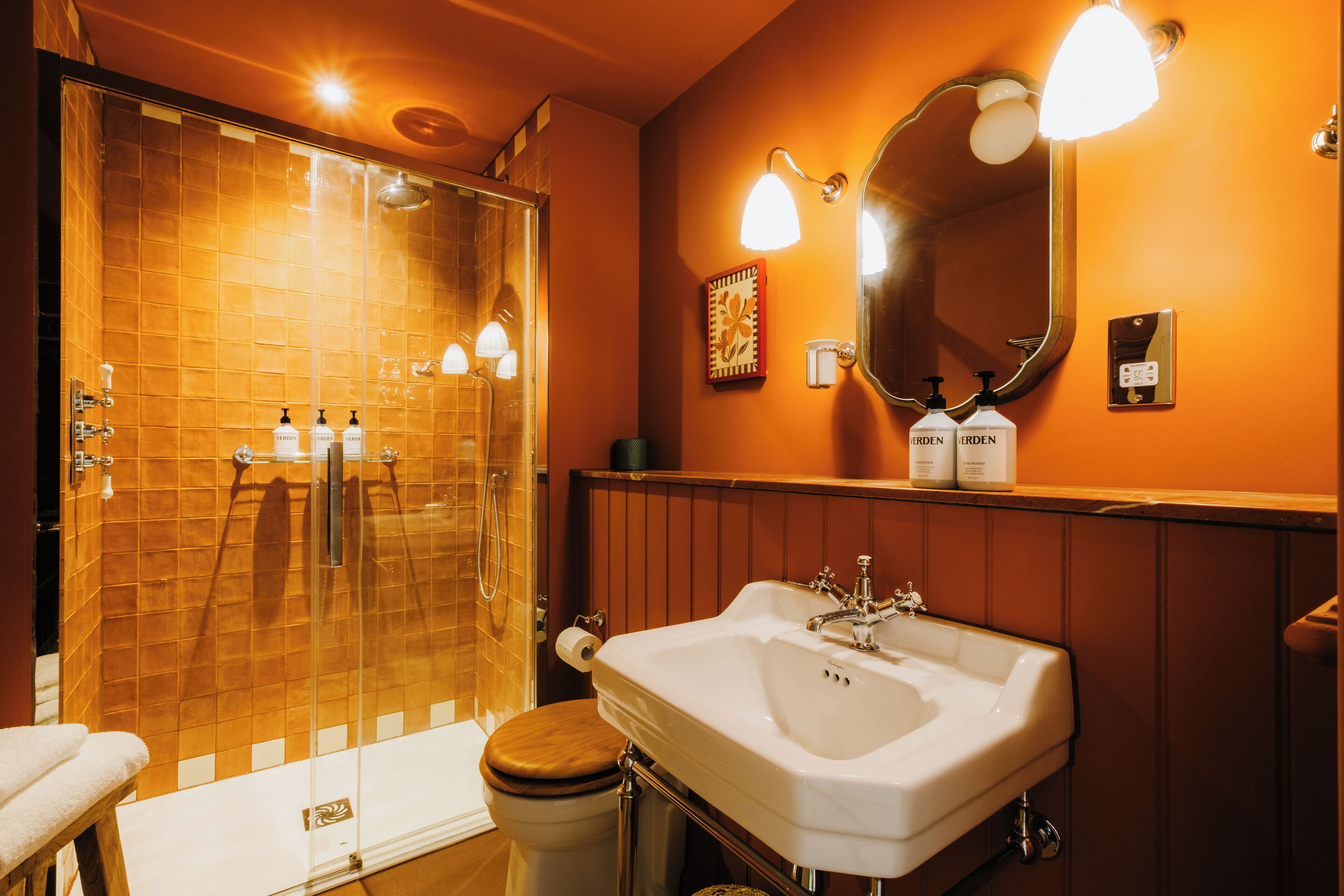 Un baño con ducha envuelta en vidrio, un lavabo blanco y un espejo.
