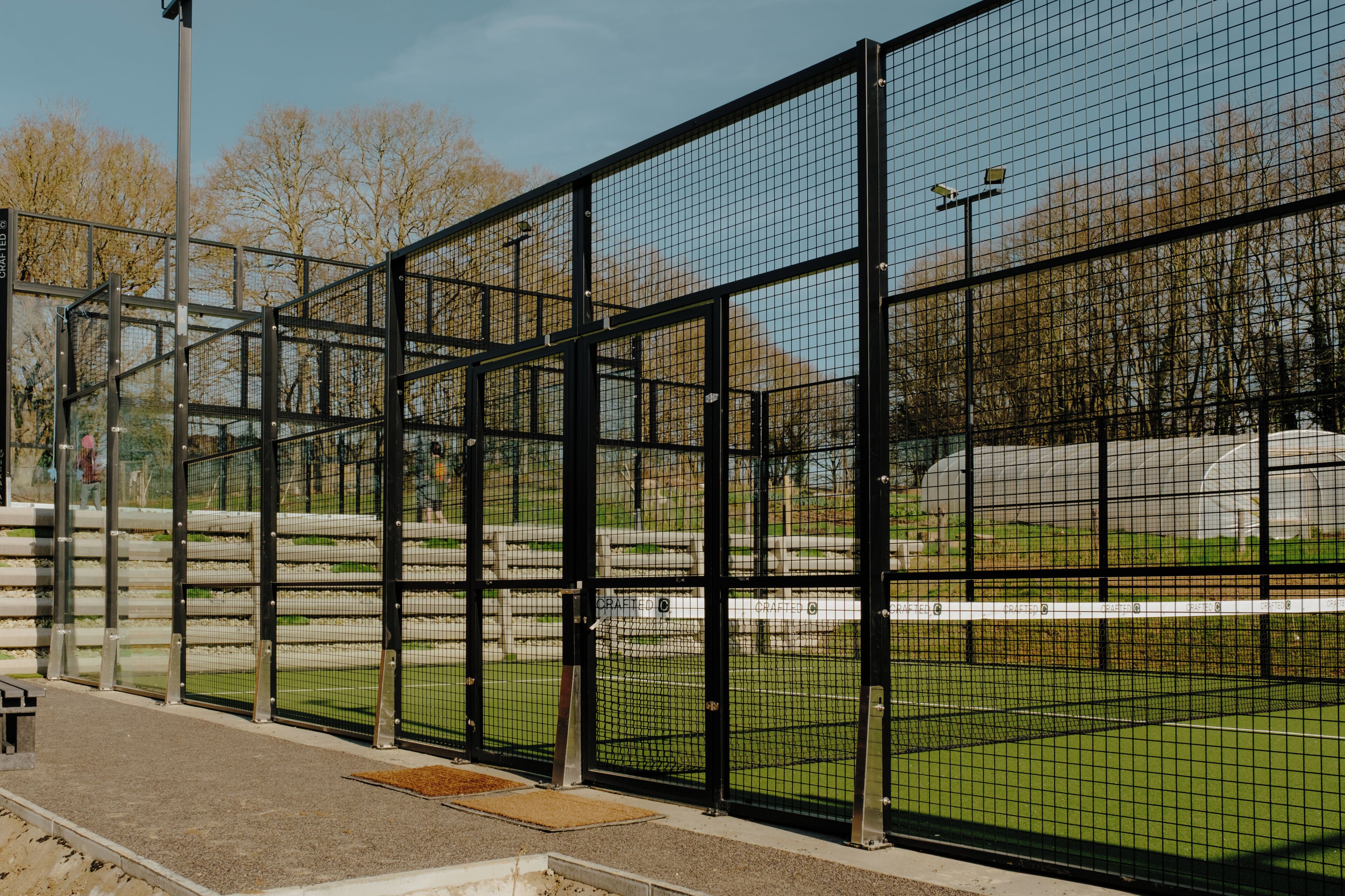 A fenced area with a bench, a grassy field, and a clear sky.