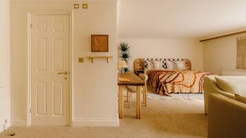 A bedroom with a bed, a wooden table, a chair, and a bedside table with a lamp.