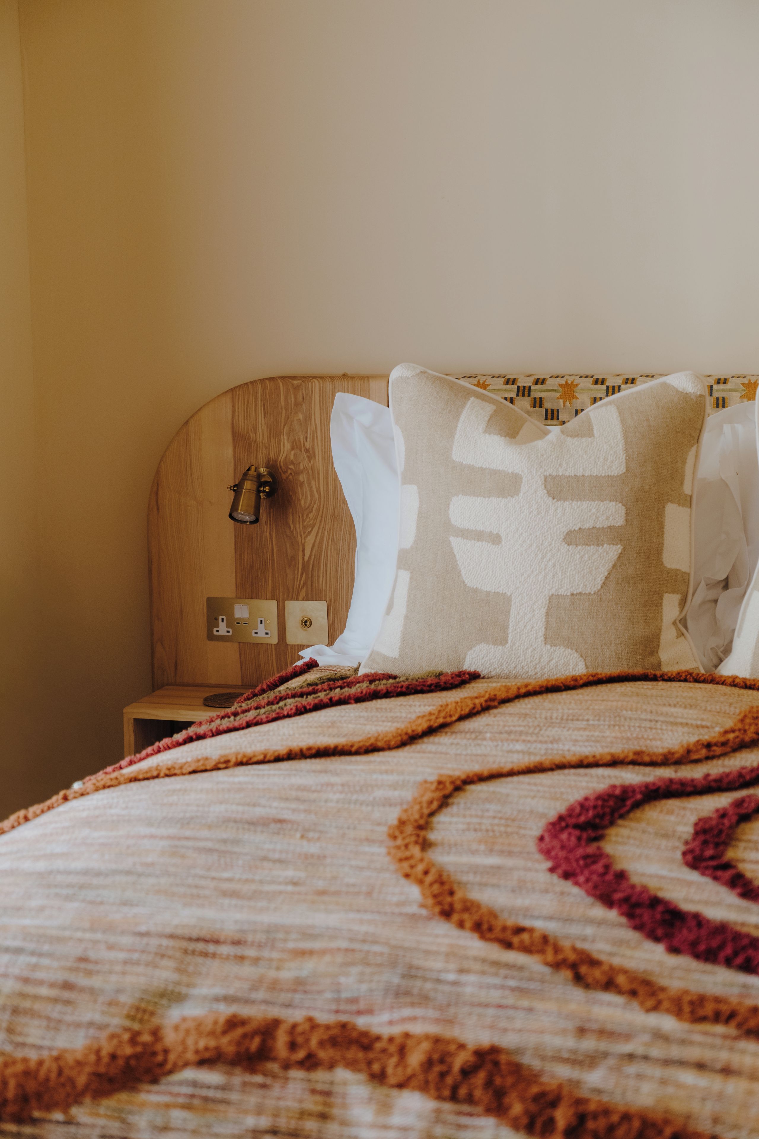 Een keurig opgemaakt bed met een bedovertrek met dessin en een decoratief sierkussen.