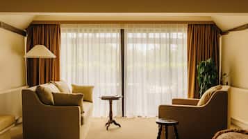 Quarto com sofá, poltrona, mesa pequena e cortinas.