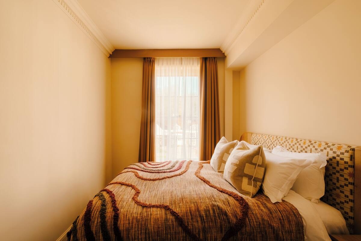 Ein Hotelzimmer mit einem Bett, Vorhängen und einem gemusterten Kopfteil.