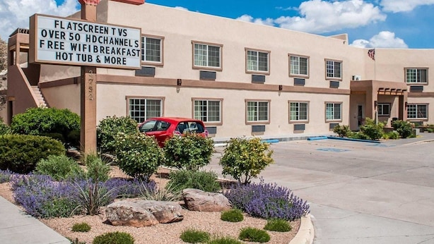 Un hotel con cartel de EconoLodge Inn & Suites, que ofrece comodidades como televisor de pantalla plana, más de 50 canales HD, WiFi gratis y desayuno, además de un jacuzzi.