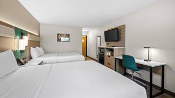 A hotel room with two beds, a desk, a chair, a TV, and a desk lamp.