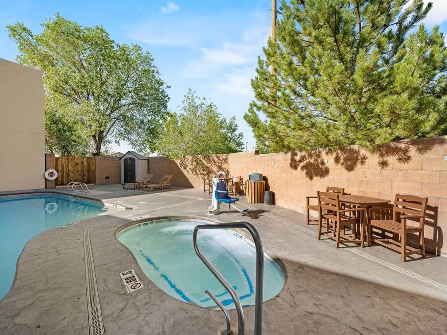 Une piscine avec une terrasse en bois, des chaises et un mur en briques.