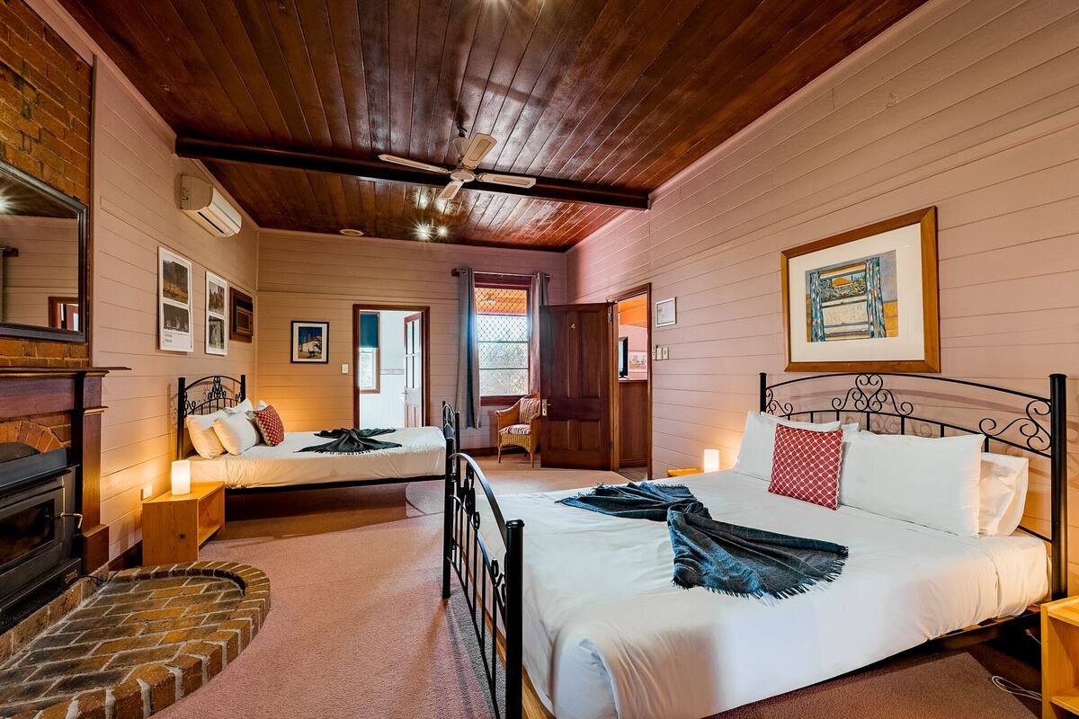A cozy room with two beds, a fireplace, and a wooden ceiling.