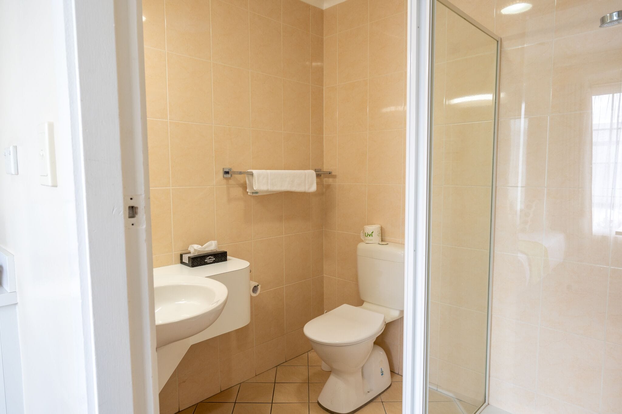 A small bathroom with a toilet, sink, and a glass shower enclosure.