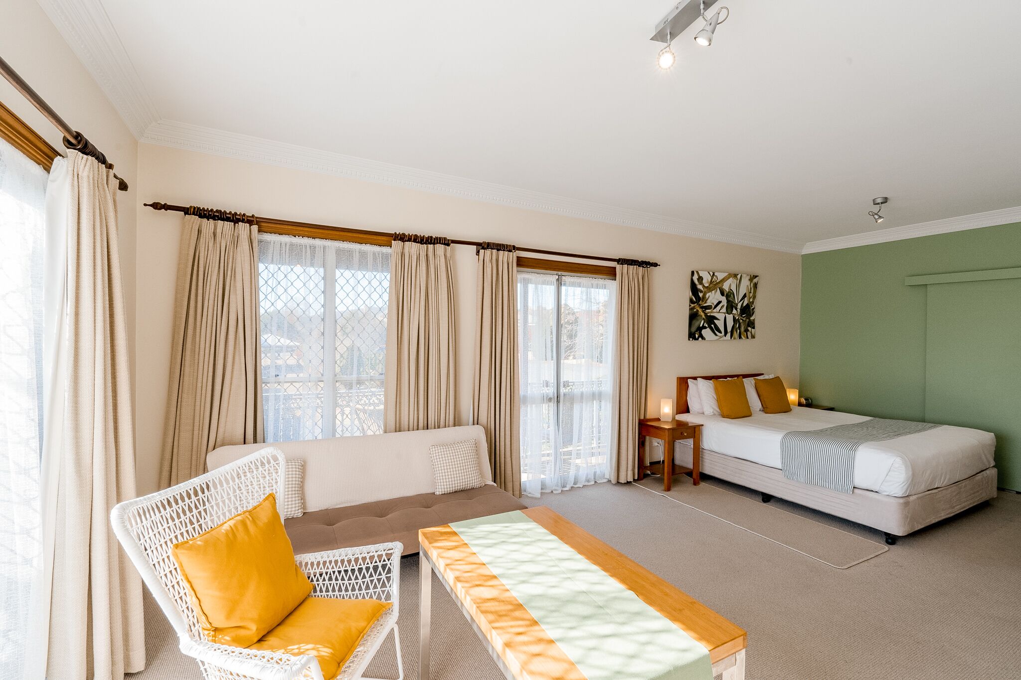A room with a bed, a sofa, a small table, and a chair.