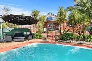 A pool area with a reception desk, outdoor seating, and palm trees. - Comfort Inn Coach & Bushmans (Seymour)