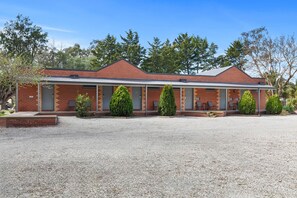 A two-story brick building with a covered outdoor seating area and a gravel driveway. - Comfort Inn Coach & Bushmans (Seymour)
