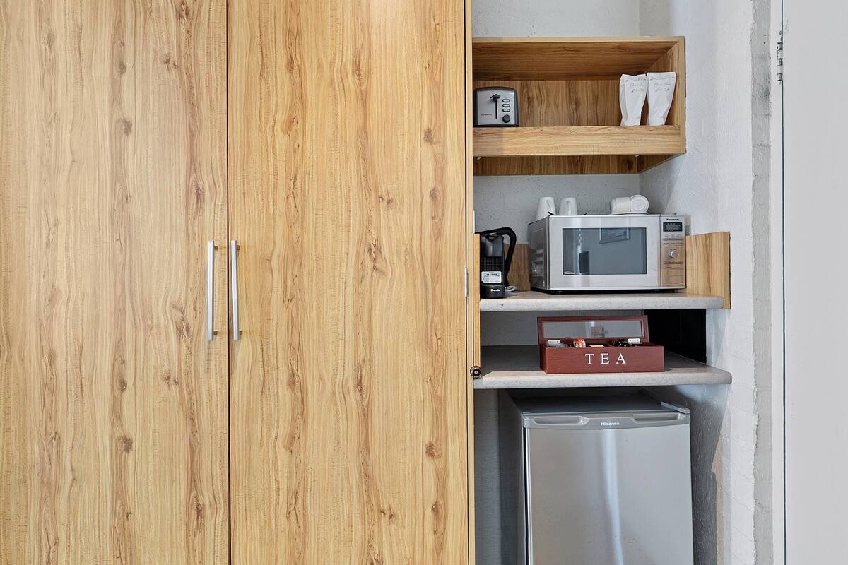 A compact kitchenette with a microwave, coffee maker, and a tea box.