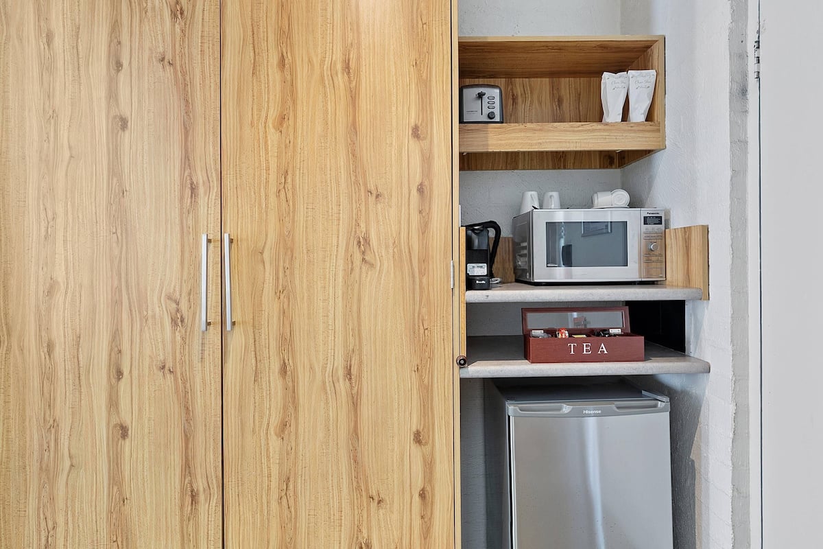 A compact kitchenette with a microwave, coffee maker, and a tea box.